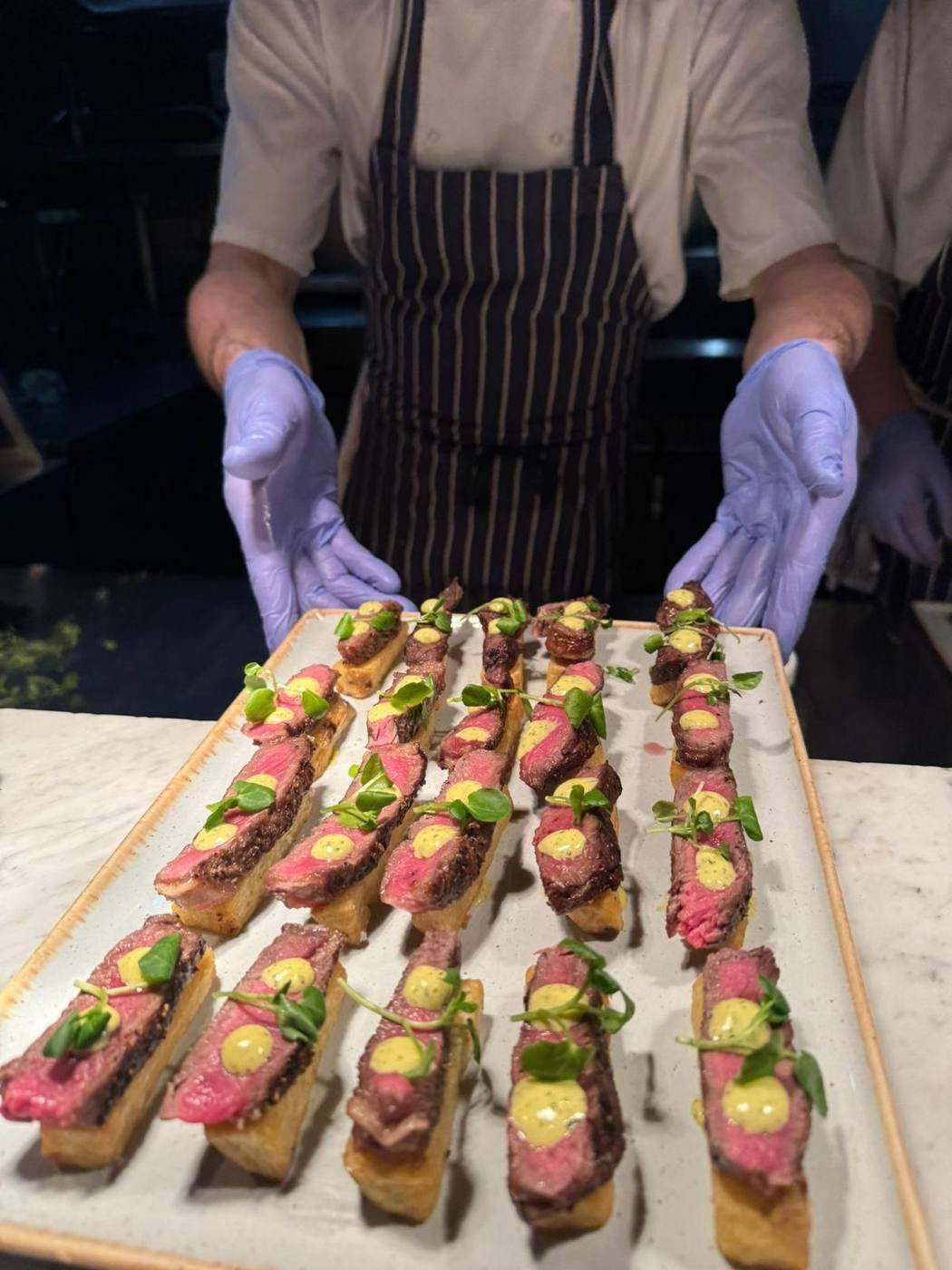 Chef arranging rare beef canapés on a serving board